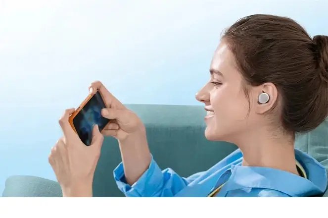 Femme écoutant de la musique avec des écouteurs Bluetooth Anker A20i tout en utilisant son smartphone.